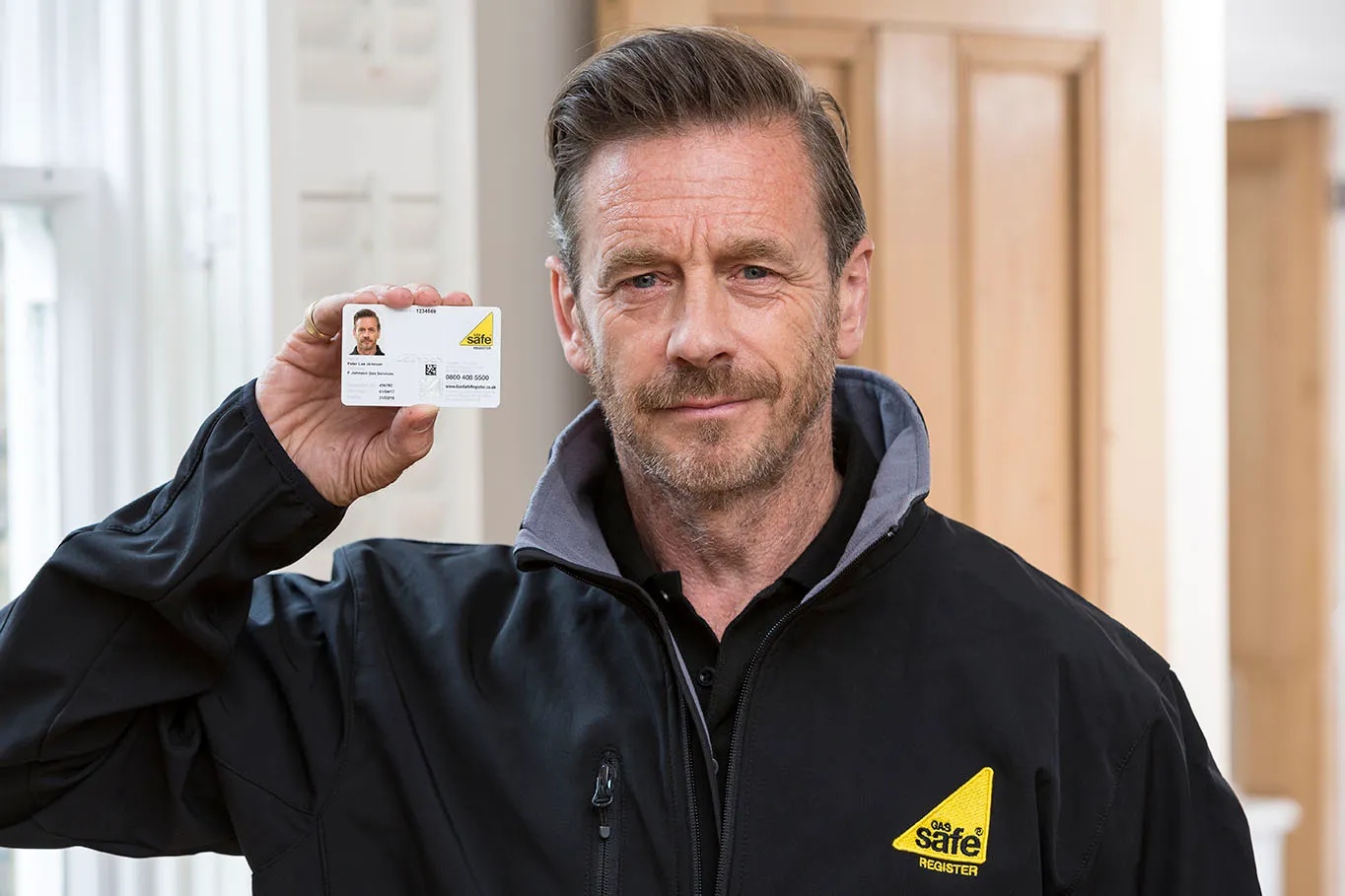 Gas Safe registered engineer holding up their ID card for inspection